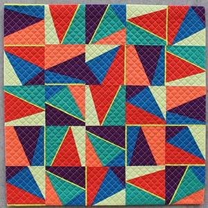 A modern, mini quilt using bright colorful triangles and slivers of bright yellow, with a diagonal grid quilting pattern.