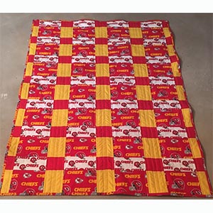 A patchwork yellow, red and white Kansas City Chiefs quilt.