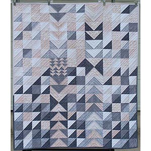 A modern quilt made with half square triangles and flying geese blocks.